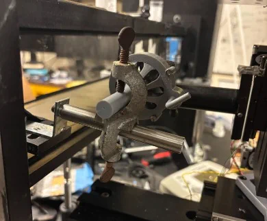 Grey 3D-printed geared handle on a rod, held by a metal C-clamp in the tunnel frame.