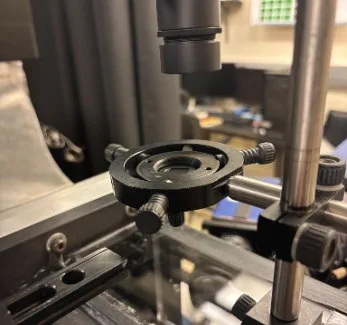 Black ring mount with three knurled screws on a vertical post under an optic.