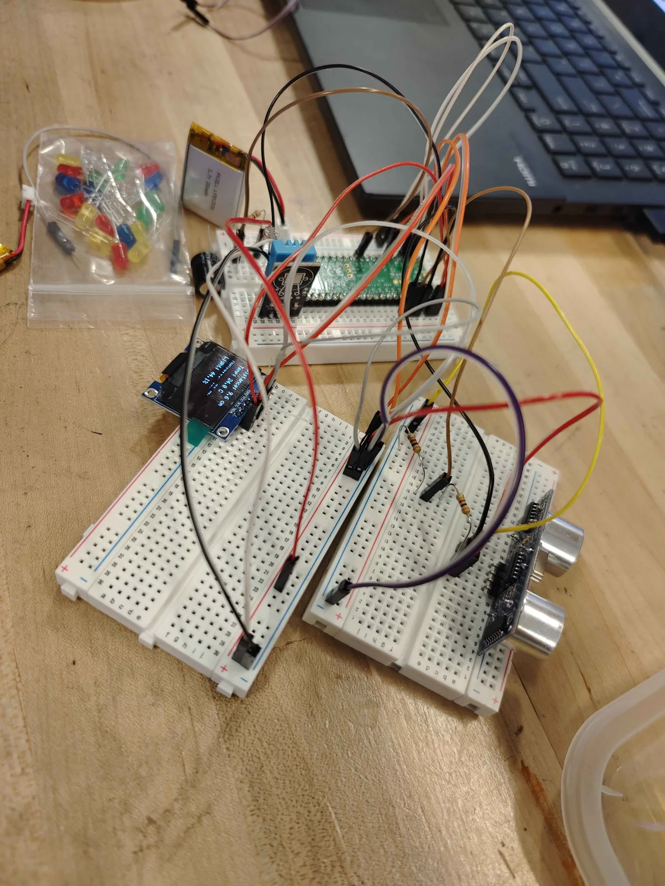 Two breadboards with an OLED screen, ultrasonic sensor and many jumper wires.