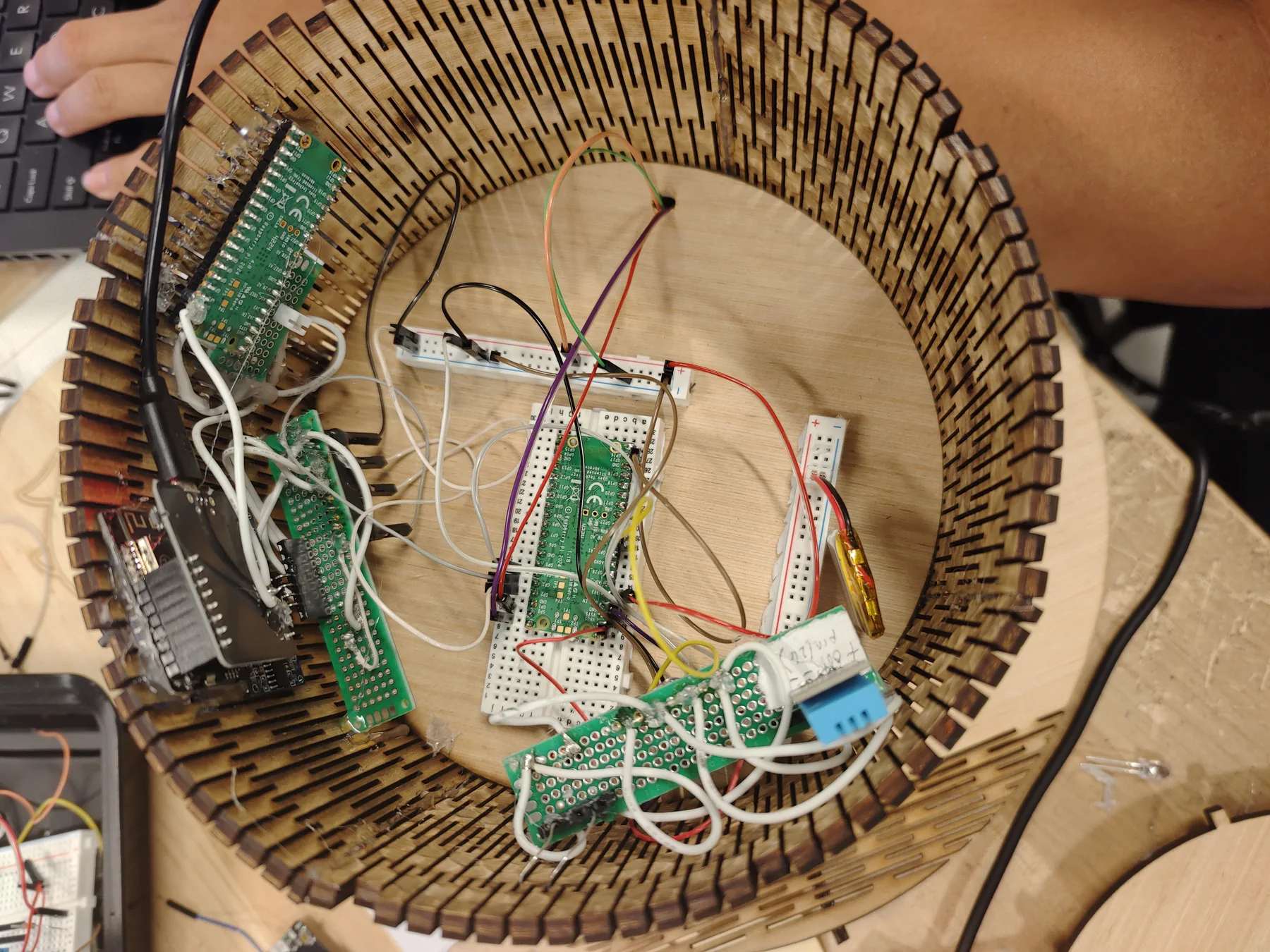 Top-down view into a plywood hat crown packed with circuit boards and wires.
