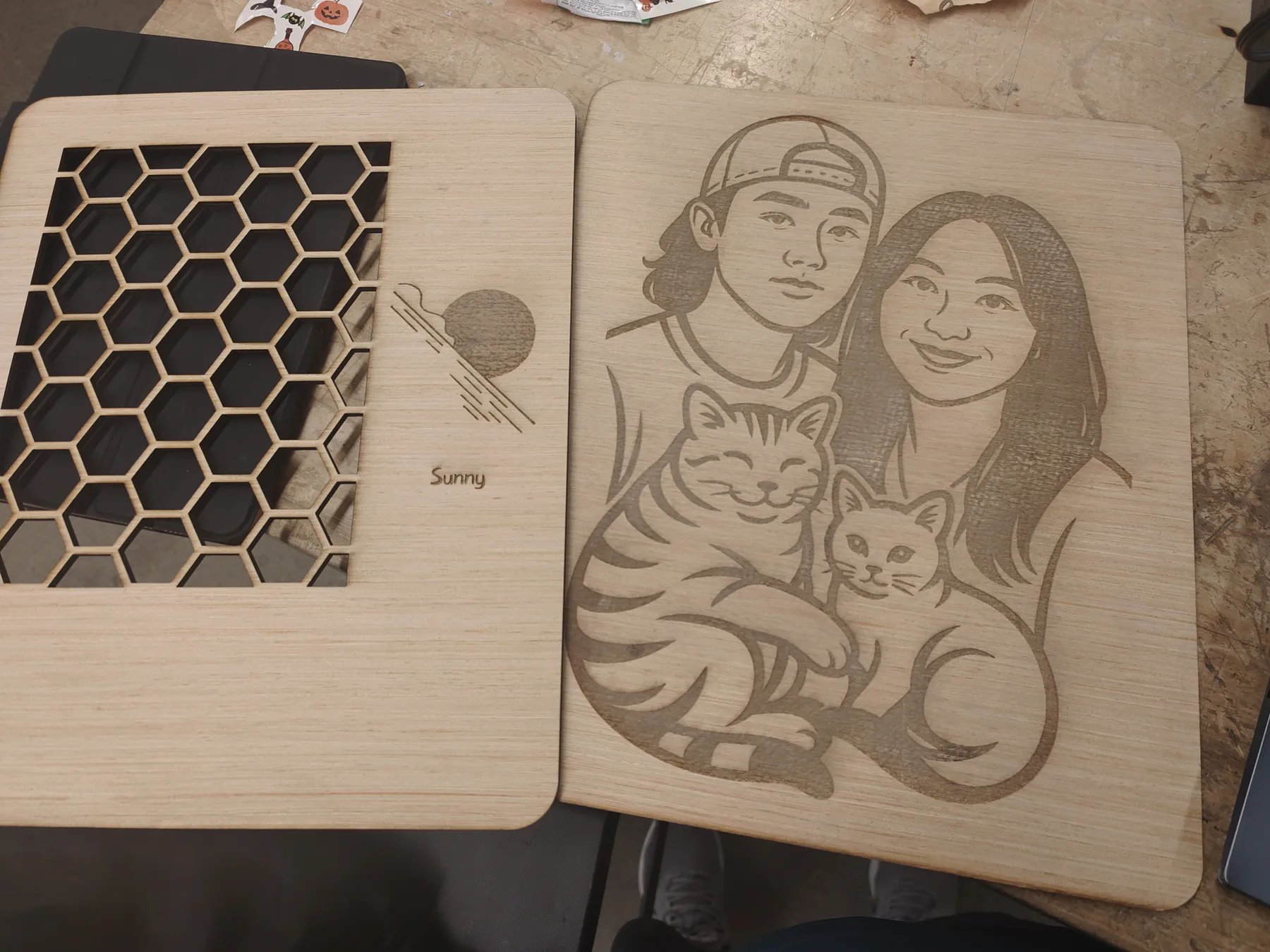 Two plywood panels, one with a hexagon vent and one engraved with a couple and two cats.