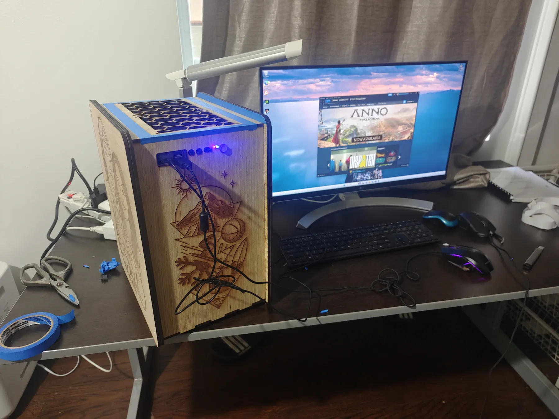 Plywood PC case with engraved panels on a desk next to a monitor and keyboard.