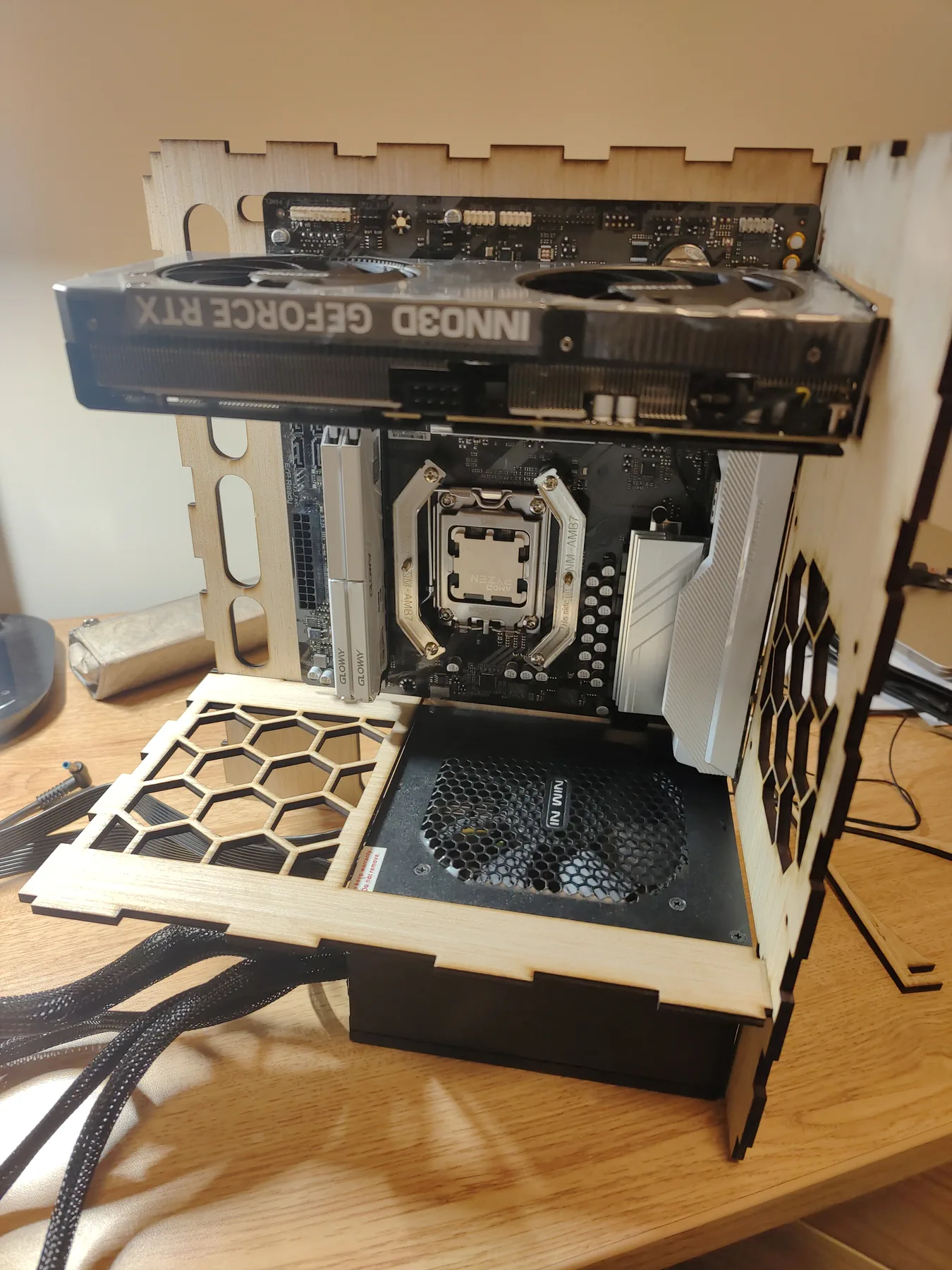Open plywood PC frame with the graphics card at the top and the power supply at the bottom.