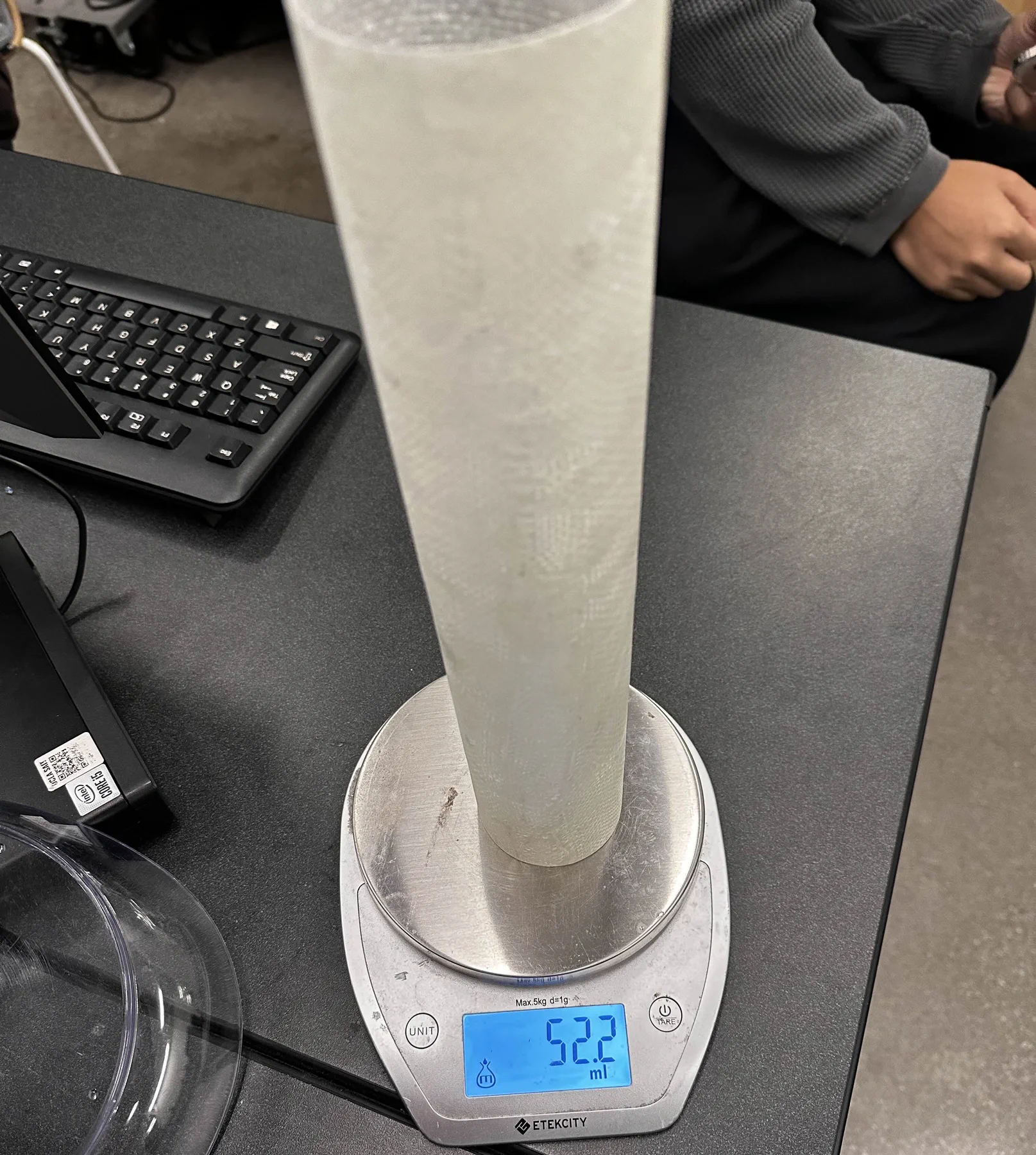 Translucent fiberglass tube standing on a kitchen scale.